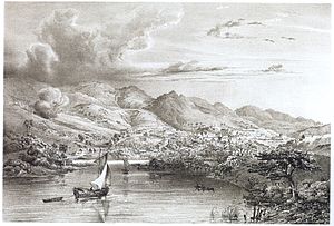 Engraving depicting two small boats sailing into a bay backed by high mountains at the foot of which are the buildings of a town