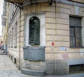 Памятный горельеф на фасаде дома. По сторонам видны белые доски с отметкой уровня наводнения 1824 г. на русском и немецком языках