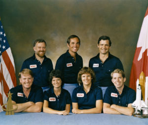 внизу слева-направо, — астронавты: Джон МакБрайд (пилот); Салли Райд, Кэтрин Салливэн и Дэвид Листма (специалисты полёта). Наверху, также слева-направо: Пол Скалли-Пауэр (специалист по полезной нагрузке), Роберт Криппен (командир экипажа) и Марк Гарно (канадский специалист по полезной нагрузке)